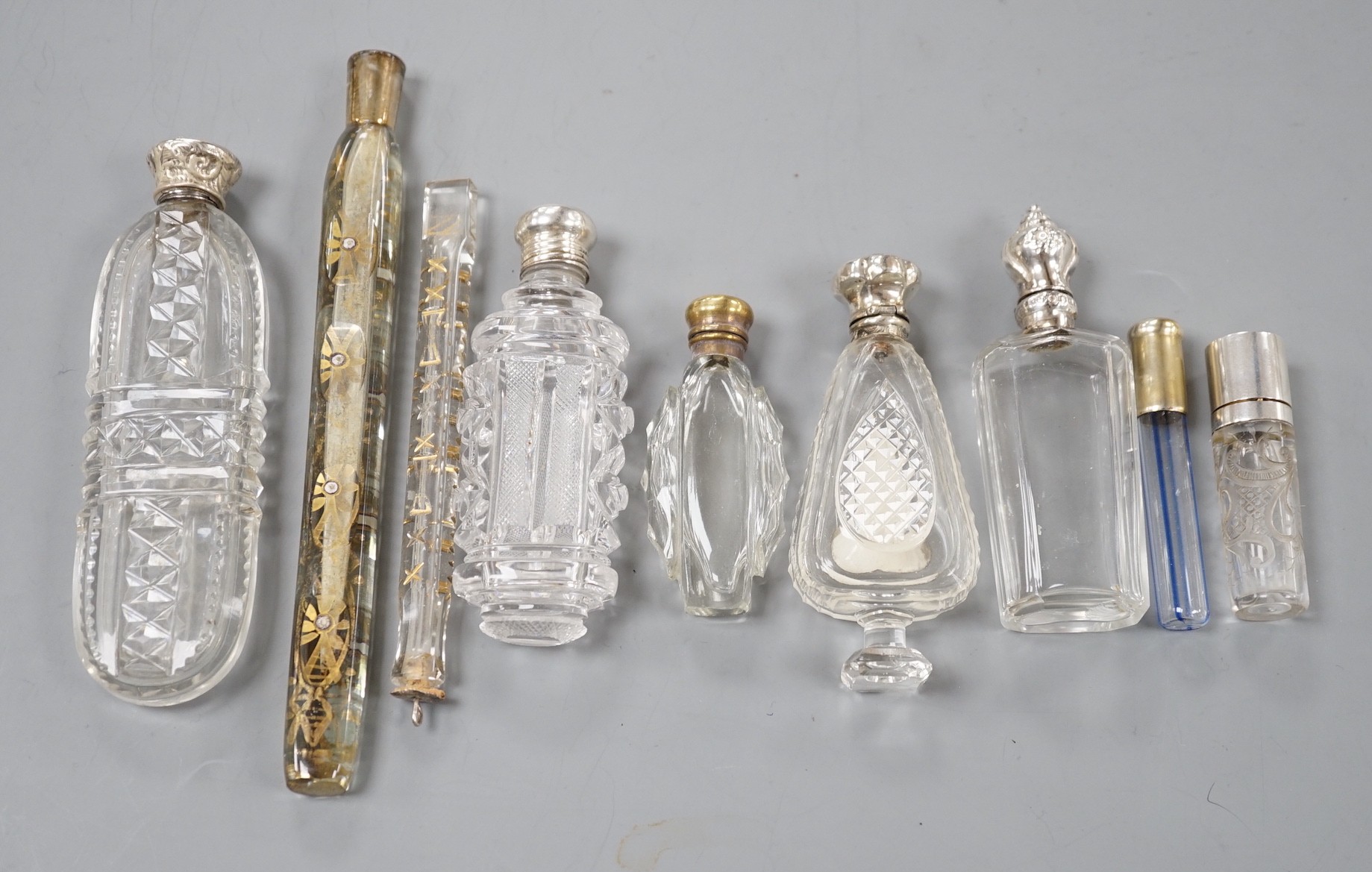 Nine assorted late 19th/early 20th century white or gilt white metal mounted glass scent bottles, including Austro-Hungarian gilt white metal and enamel mounted cylindrical scent by George Adam Scheid, largest 17.2cm.